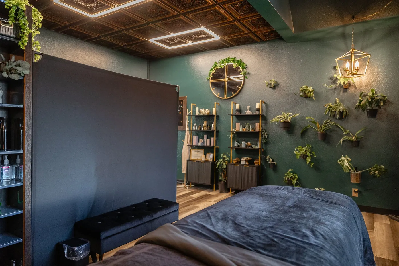 The emerald-green treatment room at BEEs Day Spa in Coeur d'Alene, with brass lighting and a living plant wall